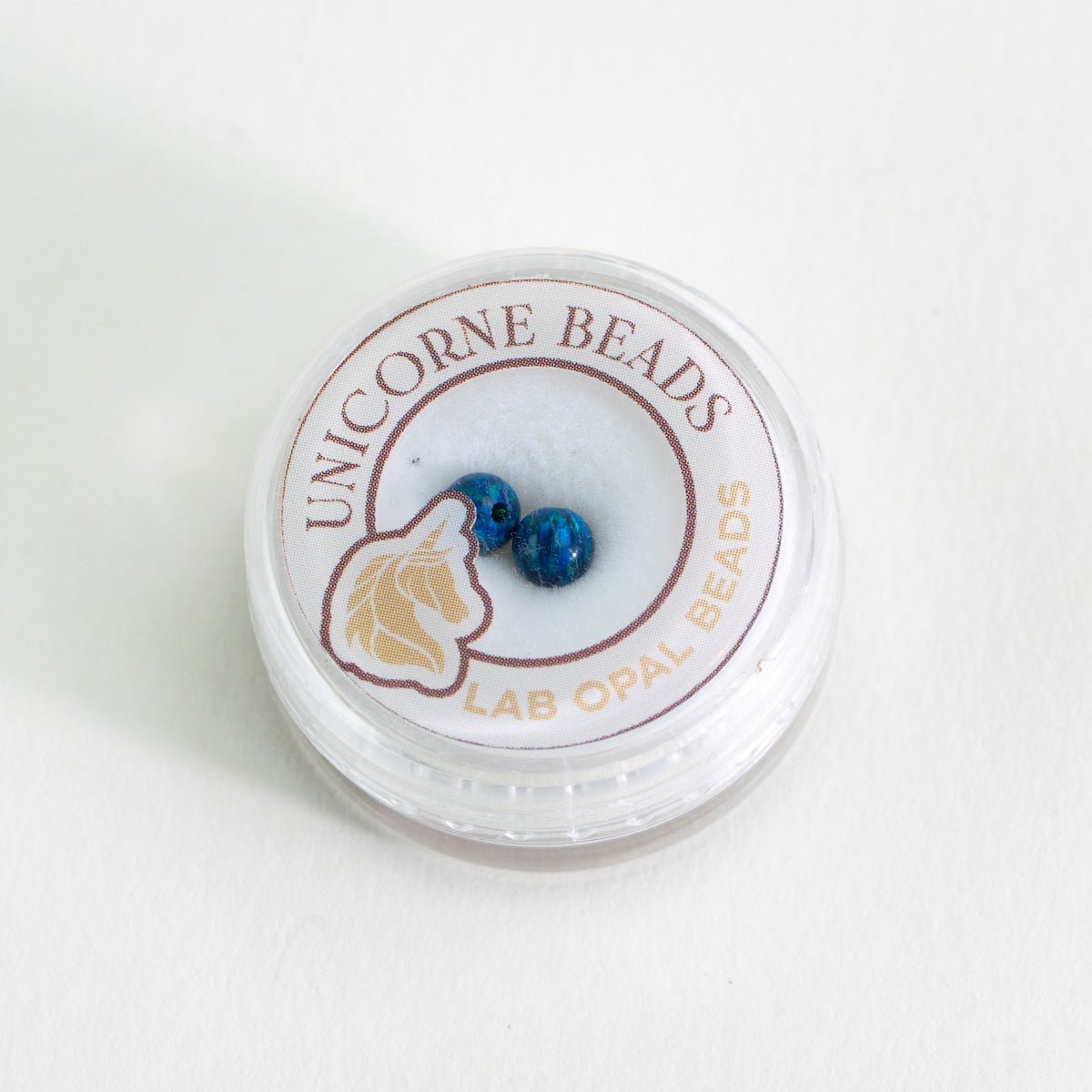 Unicorne Beads container with blue beads on a white background