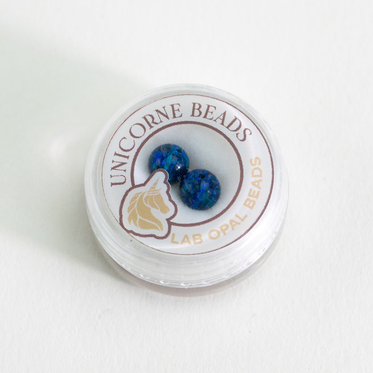 Unicorne Beads container with blue beads on a white background