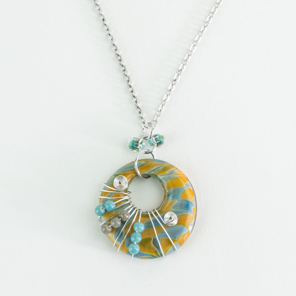 Close up of Aurora Sands halo swirl glass pendant and bead details