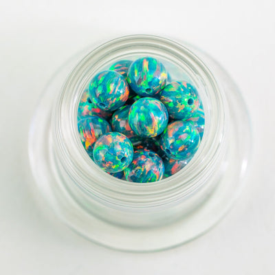 Close up of Cosmic Reef opal glass beads with teal green and iridescent tones