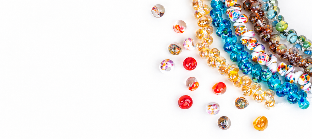 Colorful handmade glass bead strands arranged on a white background