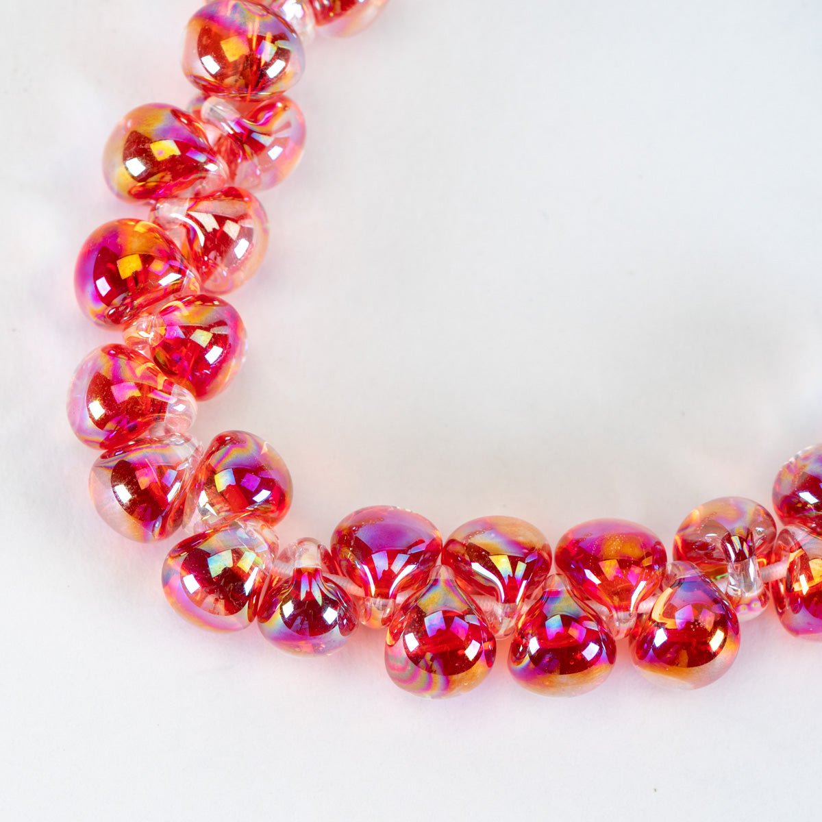A close-up of vibrant pink and red iridescent finish, arranged in a curve on a plain white background.