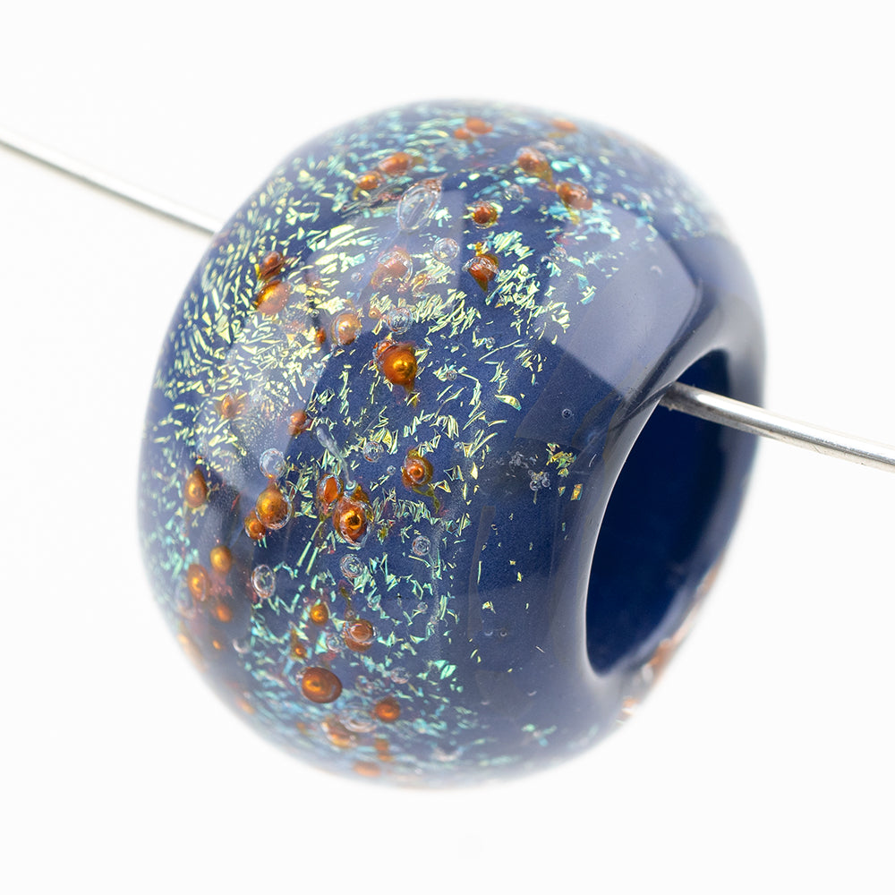One large borosilicate glass bead for jewelry. The glass bead has a deep blue hue with copper beads embedded.
