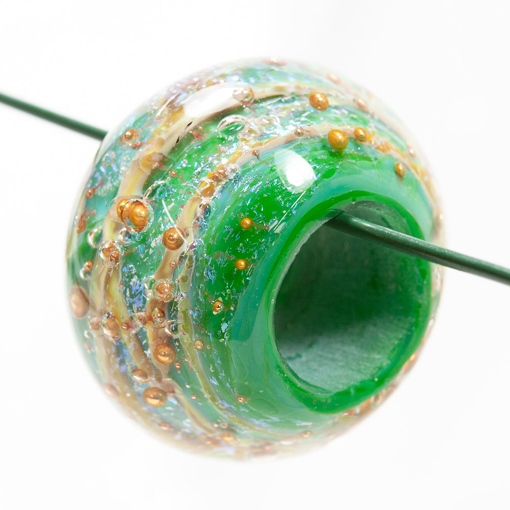 Large glass bead with a Irish green hue. The glass bead has a hole in the center with a string running through it. 