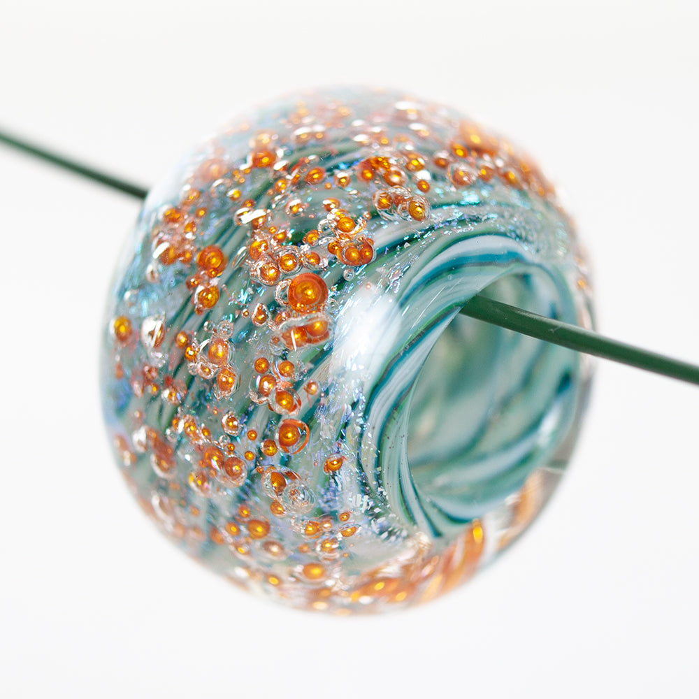 One large glass bead on a string. The bead had a mix of blue swirls and feature copper globs that embody the entirety of the bead.