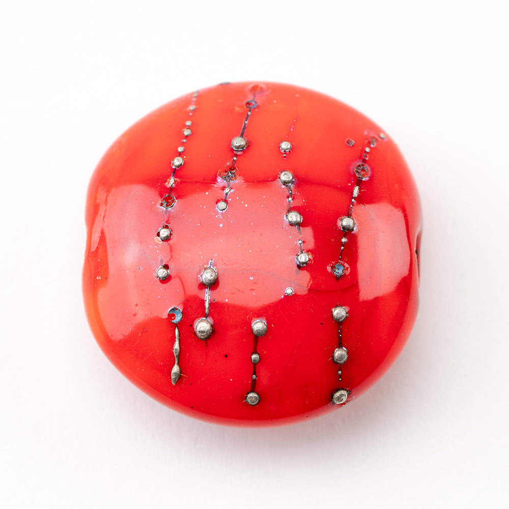 Large red glass bead with silver globs embedded. Glass bead is red in color and has two holes on each side to be used for jewelry projects.