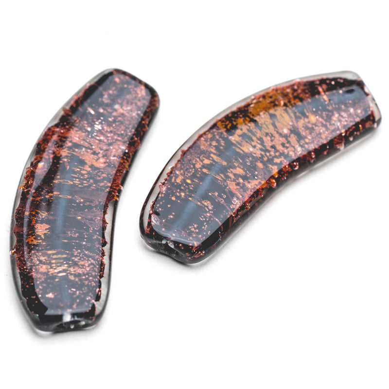Two flat, banana shaped glass beads. The beads are dark brown in color with a copper striping in the middle giving it a red hue. The beads have a glossy, smooth outer layer. Two hole are shown on each side of the beads used for jewelry makers to string through.