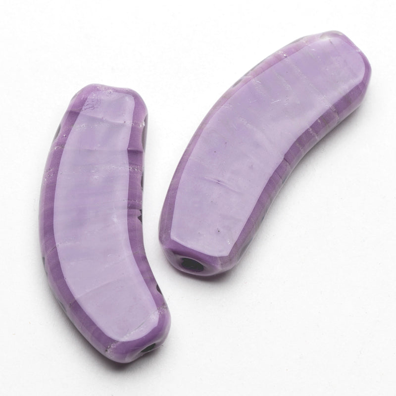 Two glass beads shaped like a flat banana. The glass beads are pastel purple in color and feature subtle texturing. The outermost layer of the bead is a clear, glossy finish.